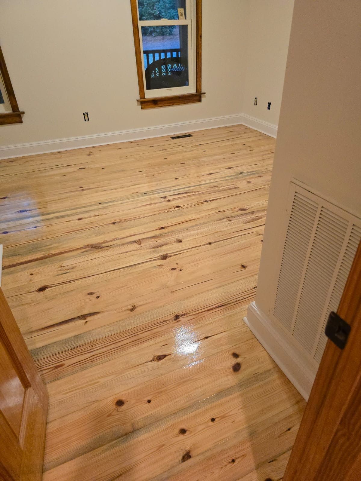 A room with a wooden floor and two windows