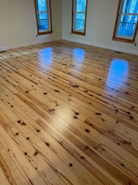 A large empty room with a wooden floor and windows.