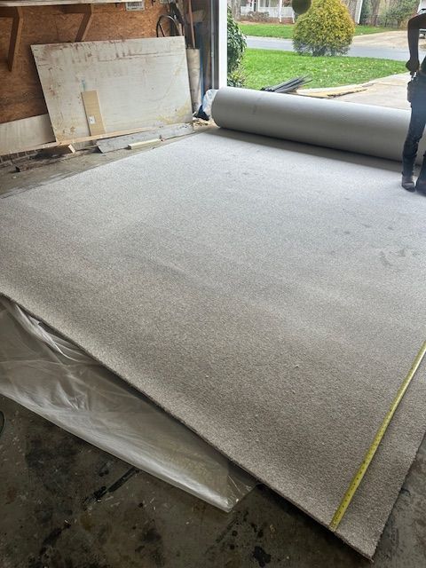 A roll of carpet is being measured in a garage.