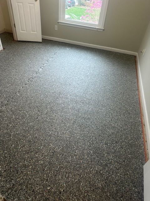 A room with a gray carpet and a window.