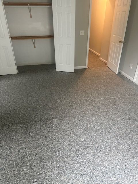 An empty bedroom with a gray carpet and a closet.