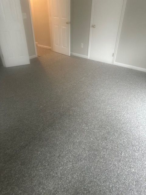 A bedroom with a gray carpeted floor and white walls.