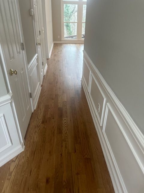 A hallway with hardwood floors and white trim in a house.