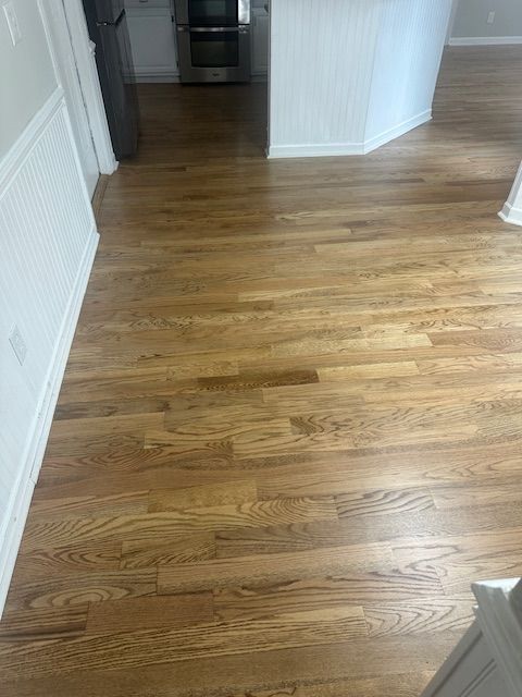 A kitchen with hardwood floors and white walls.