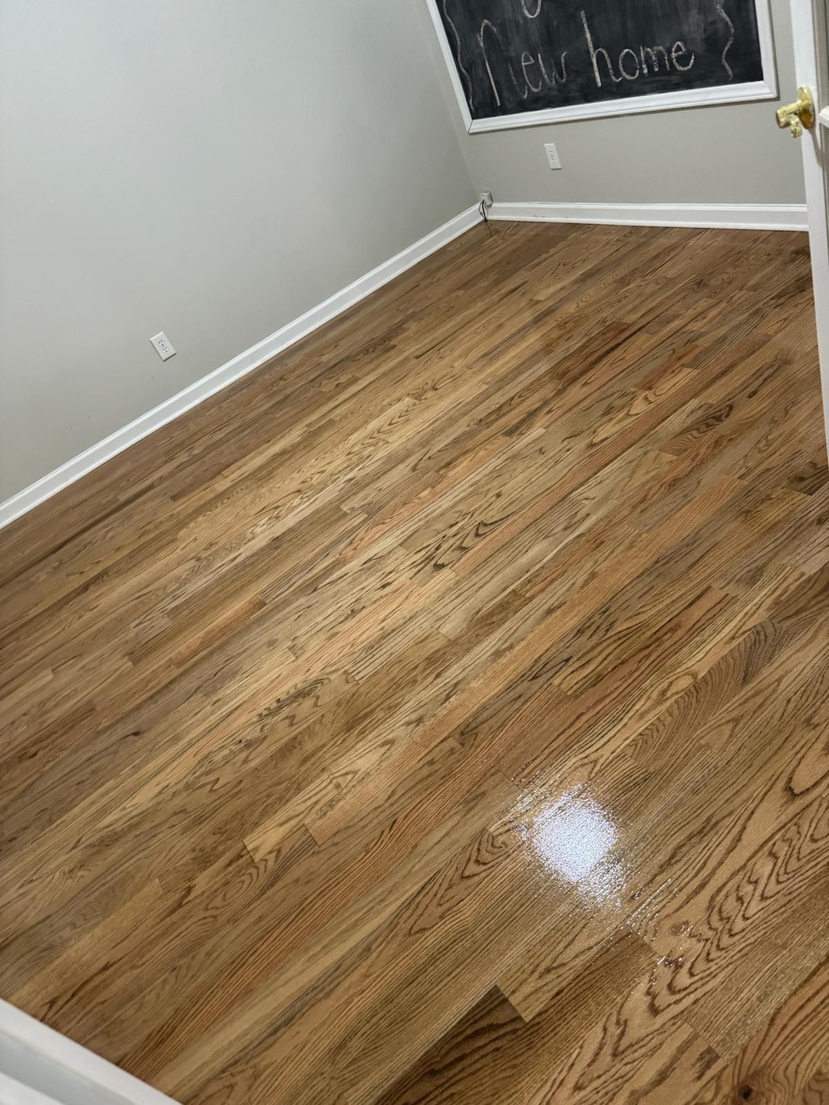 A room with hardwood floors and a chalkboard on the wall.