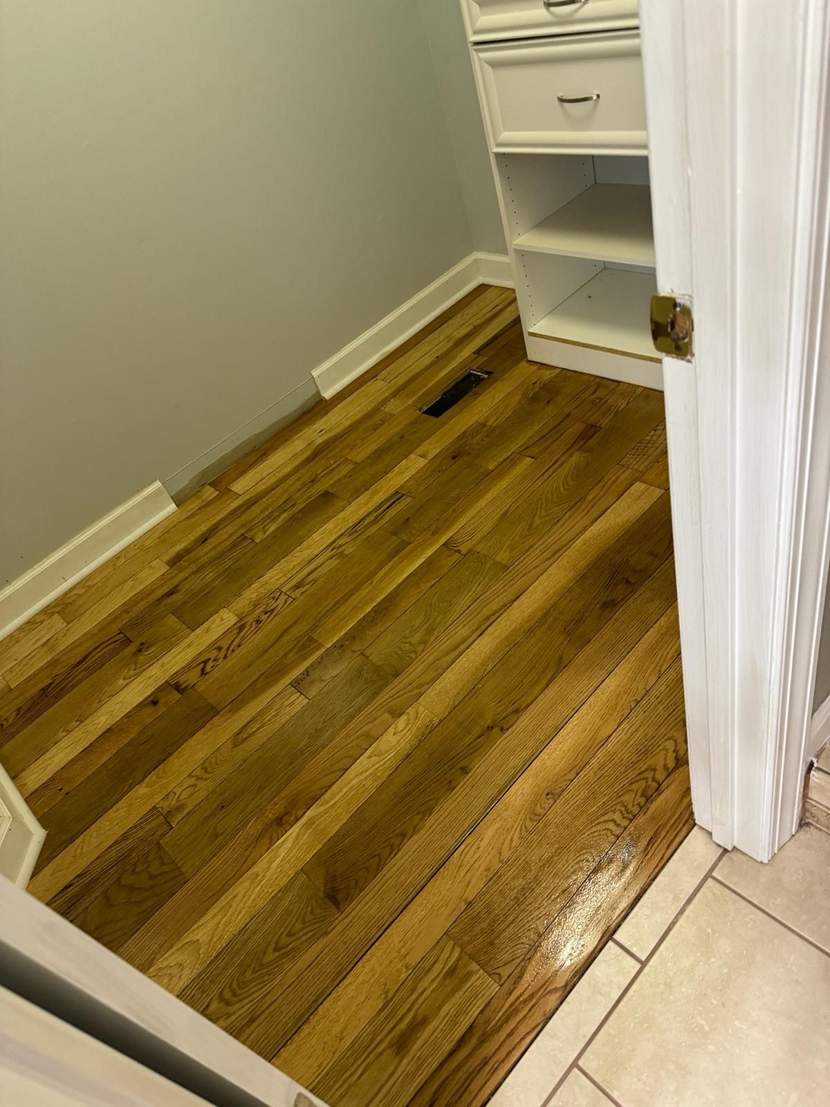A closet with hardwood floors and a white door.