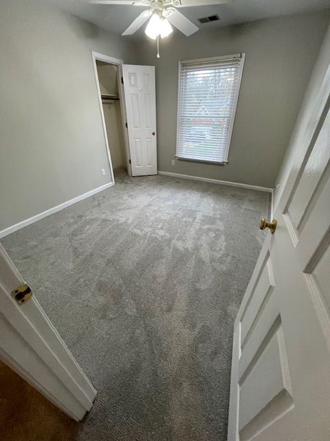 A bedroom with a ceiling fan and a window