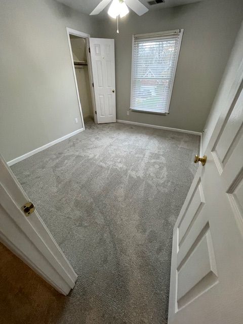 A bedroom with a ceiling fan and a window.