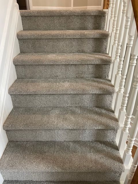 A set of stairs with carpeted steps and a white railing.