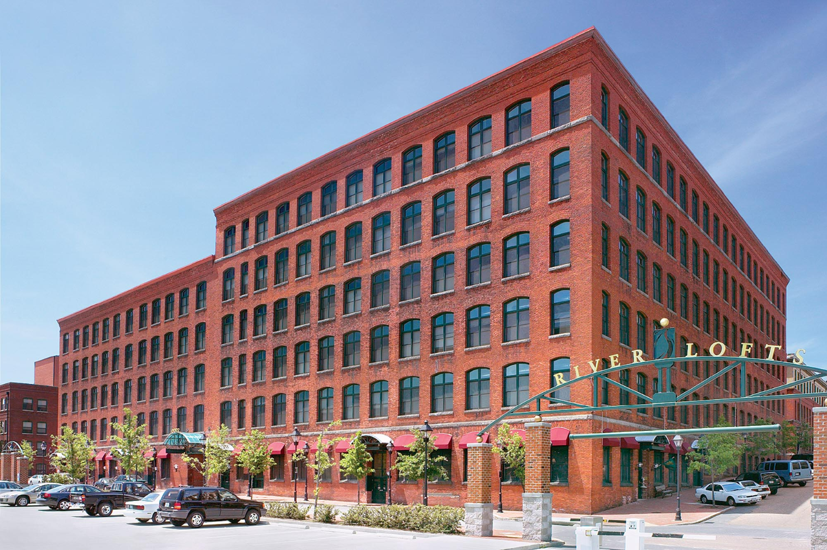 A large brick building with a lot of windows and cars parked in front of it.