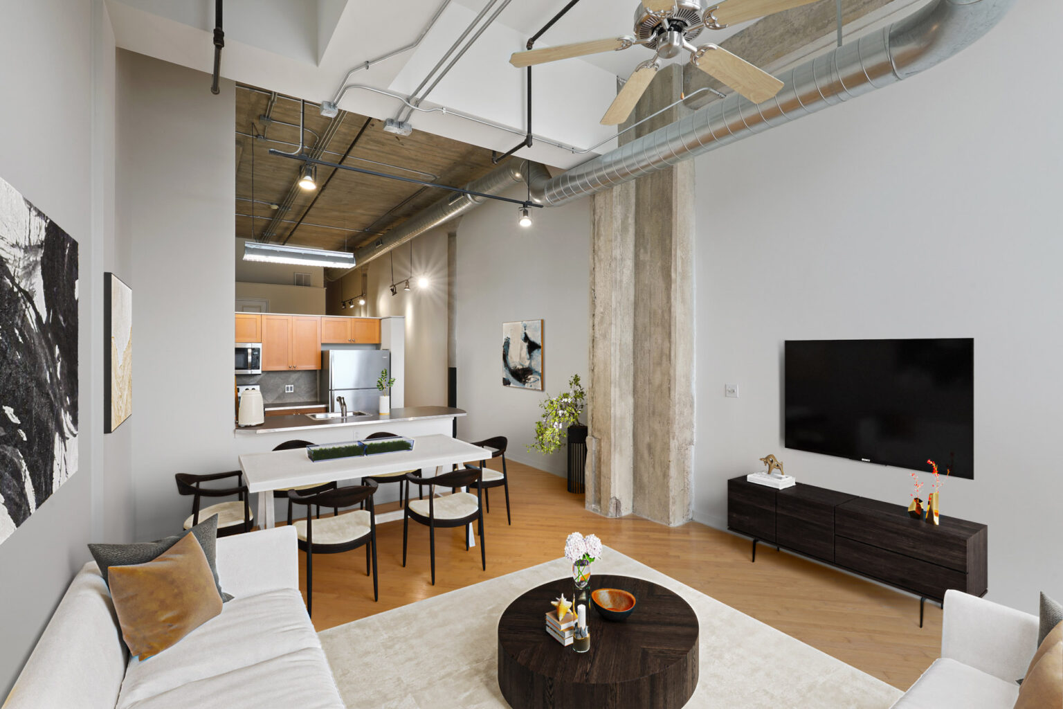 A living room with a couch , coffee table , television and ceiling fan.