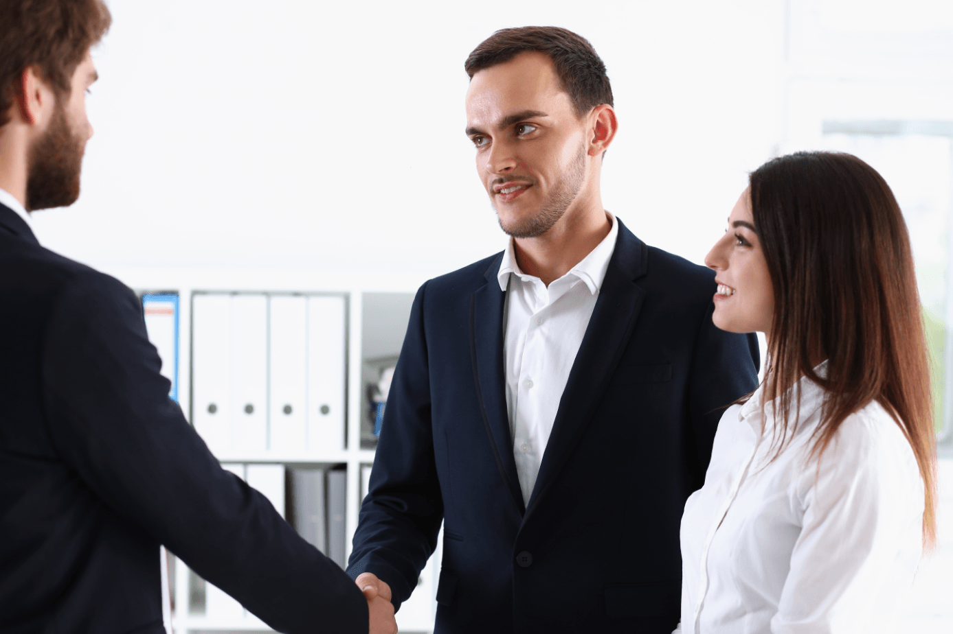 A man and a woman are shaking hands with each other in an office.