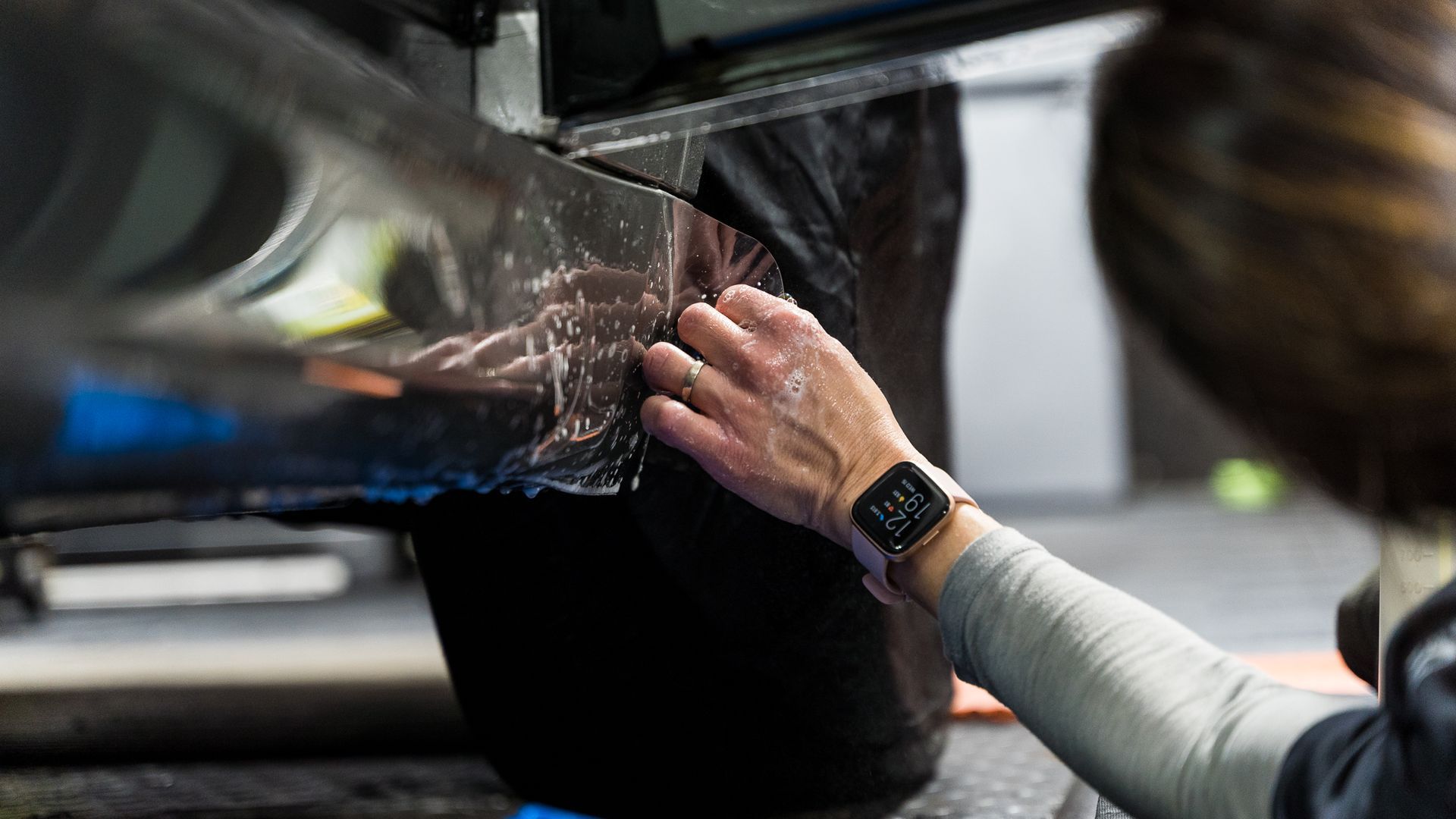A person is applying a protective film to the side of a car.