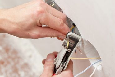 Electrician peeling off insulation from wires to install the socket