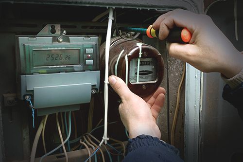 he electrician changes the old electric meter for the new
