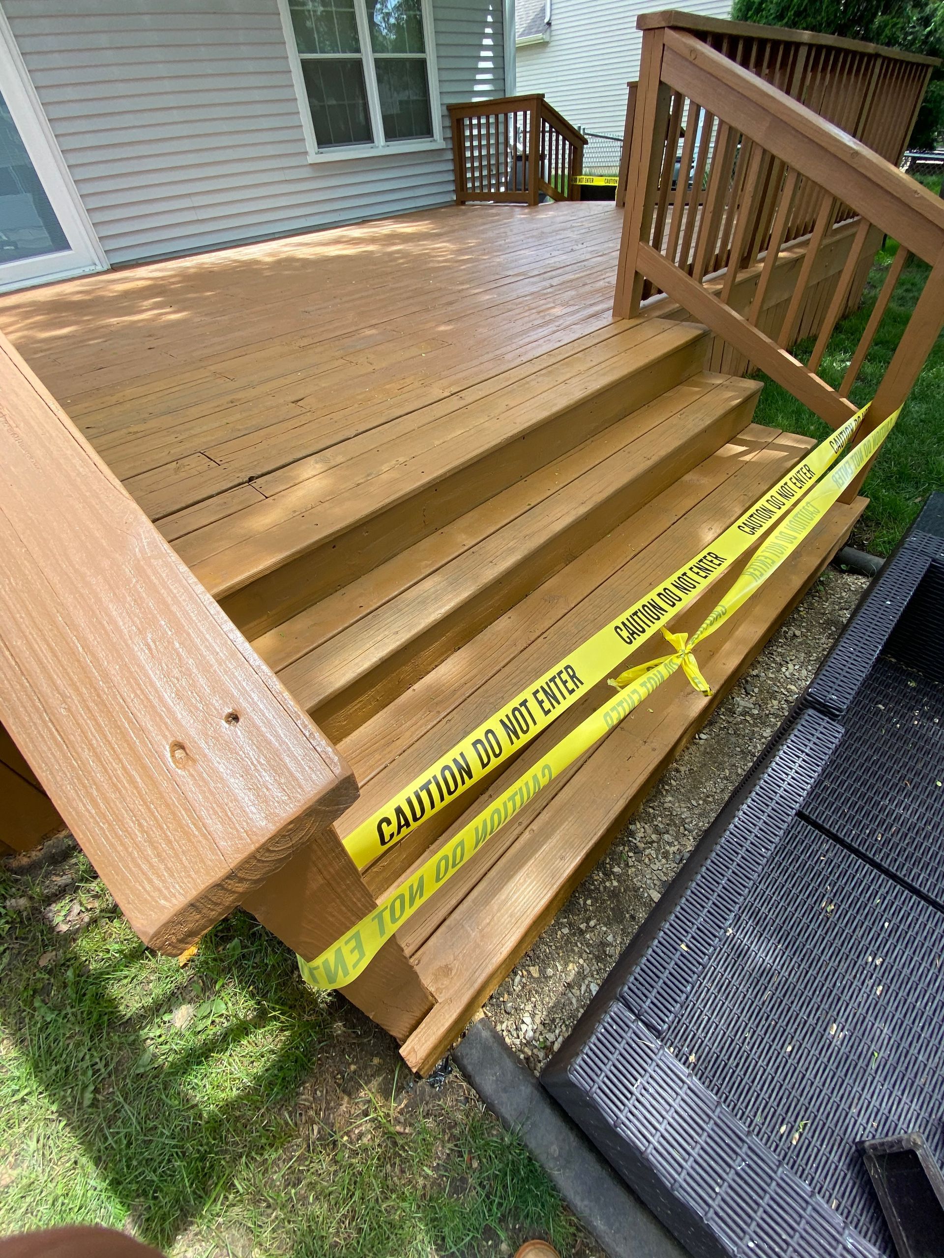 A set of brown wooden deck stairs blocked off by yellow 