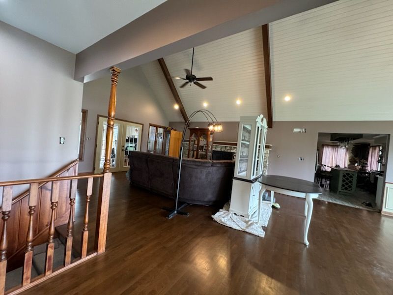 Spacious wooden interior with railing, ceiling fan, and large dark counter in the center