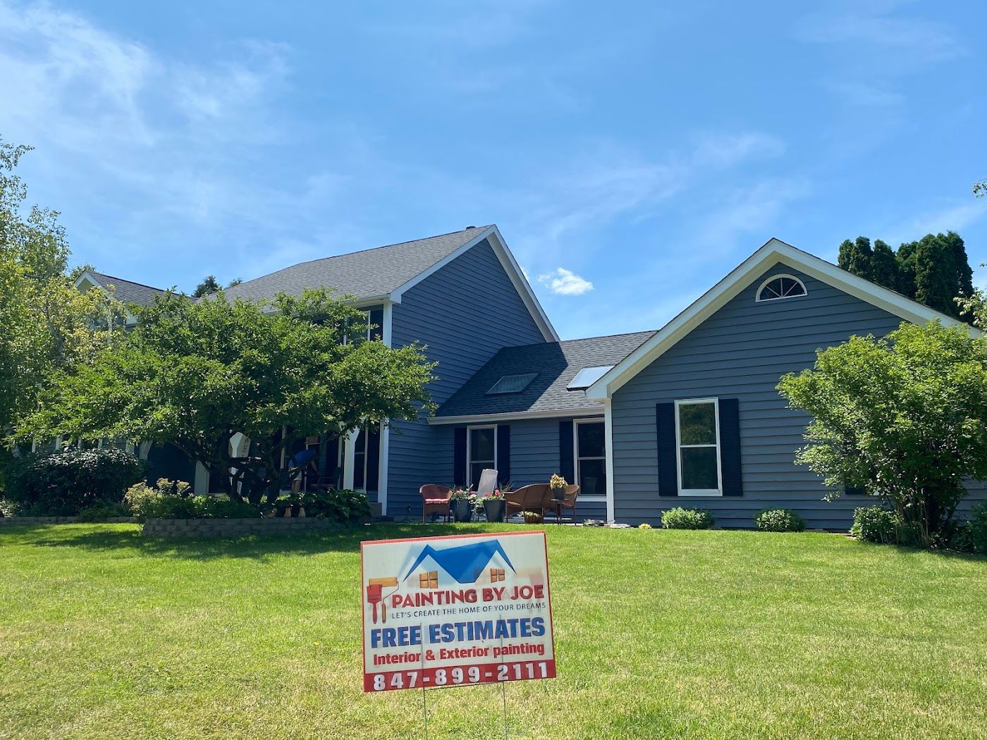 A blue, two-story house with a lawn and a 