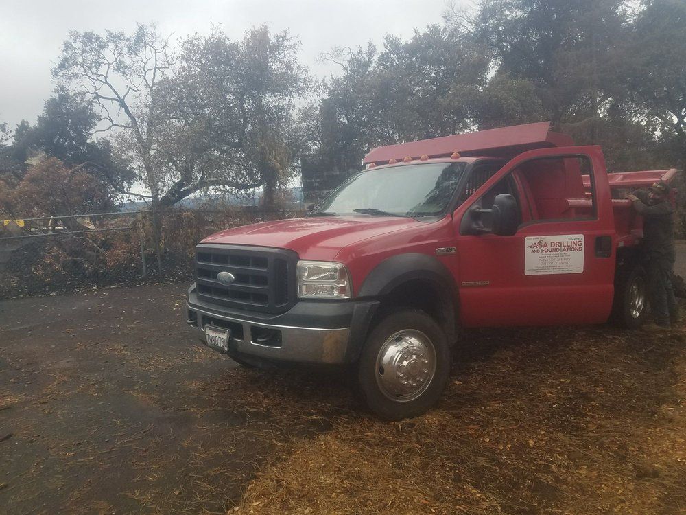 A red dump truck is parked in a dirt lot