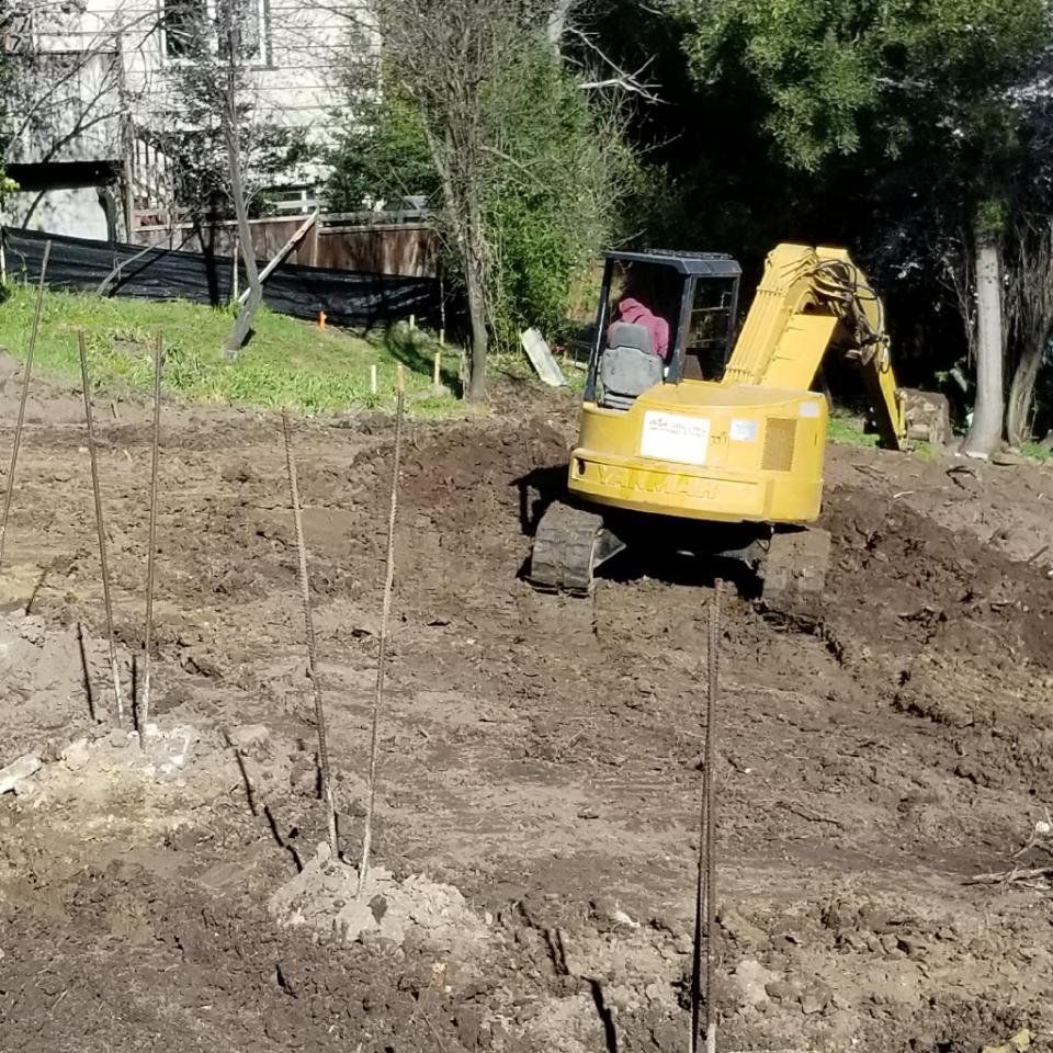 A yellow excavator is digging in a dirt field