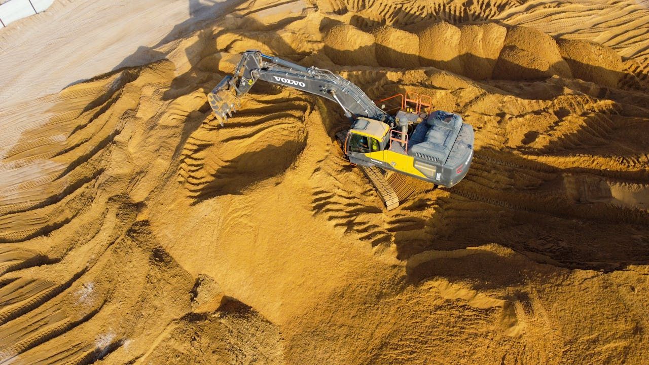 An aerial view of a bulldozer working on a pile of sand.