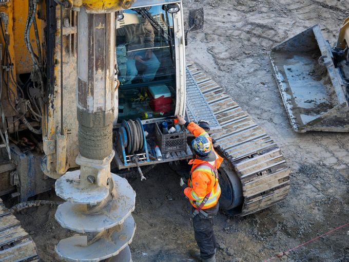 A construction worker is working on a machine on a construction site.