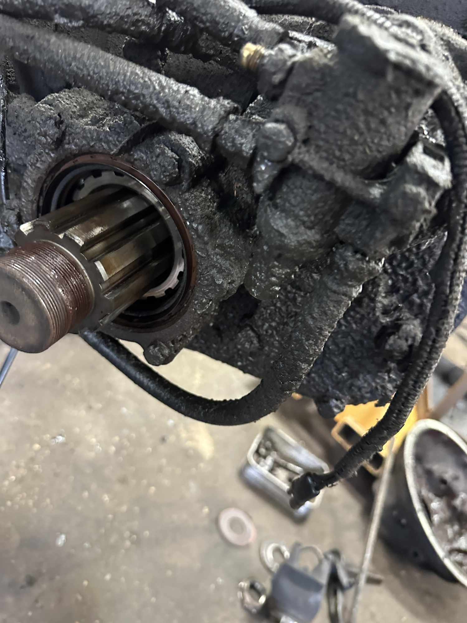 Close-up of a greasy, oil-covered mechanical component with a visible splined shaft extending outwards.