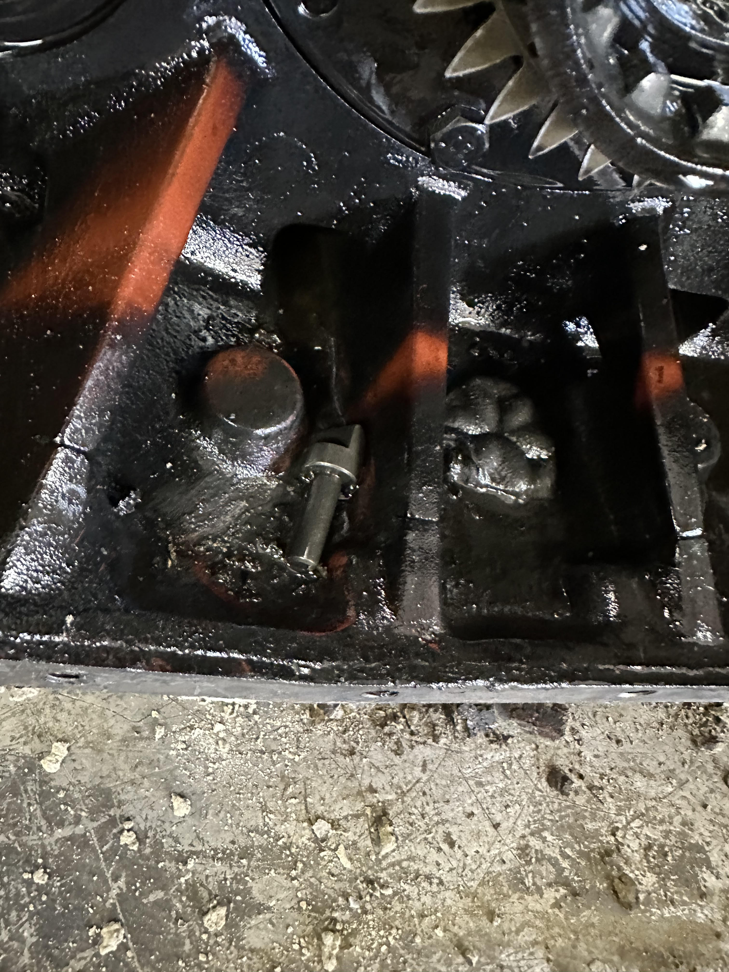 Close-up of a dark engine component with a bolt, a stud, and a cluster of rivets.