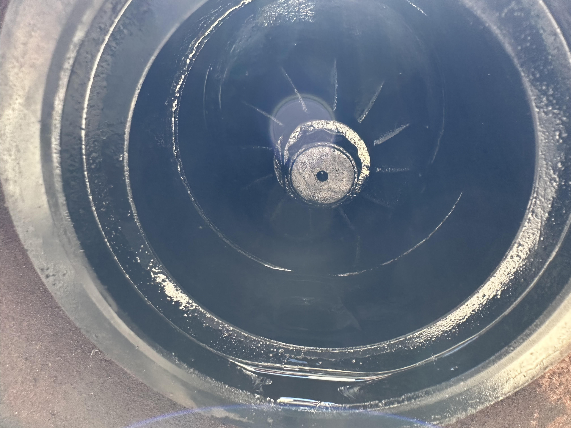 Inside view of a dark pump with blades, coated in grime.