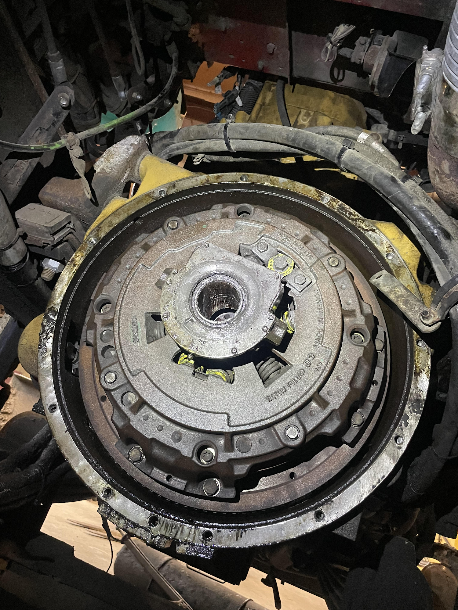 Open view of a dusty truck clutch assembly. Yellow and silver components are visible, surrounded by metal.