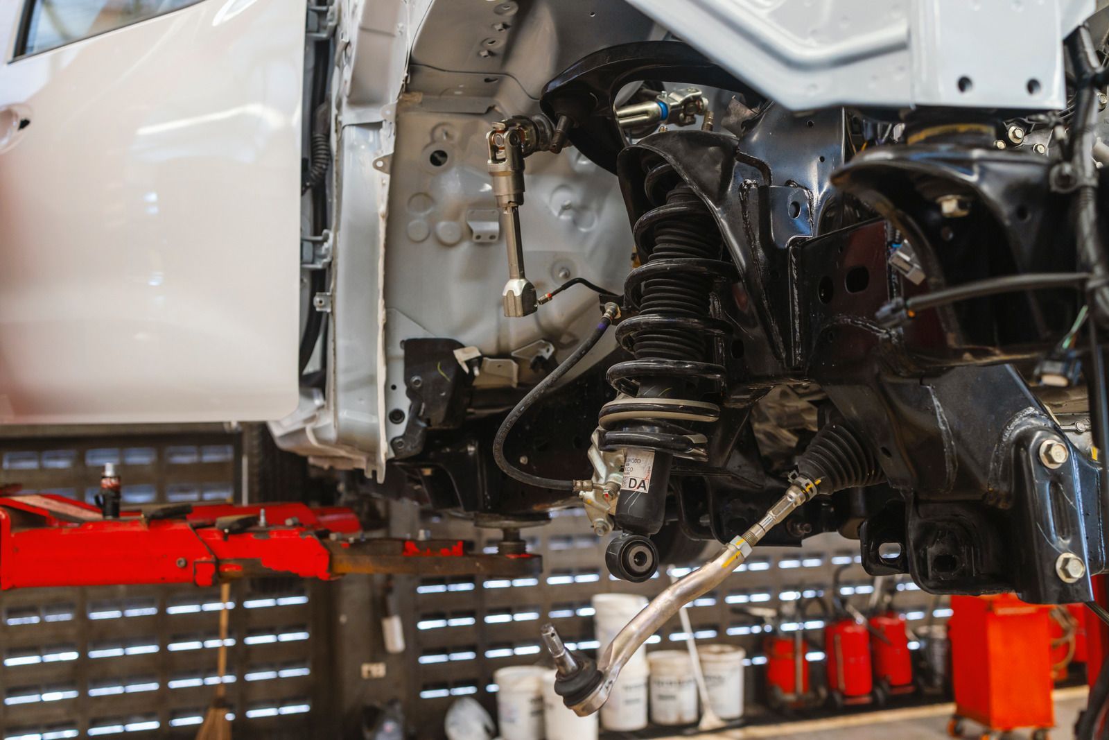 Car chassis being repaired, suspension components visible, in a workshop.