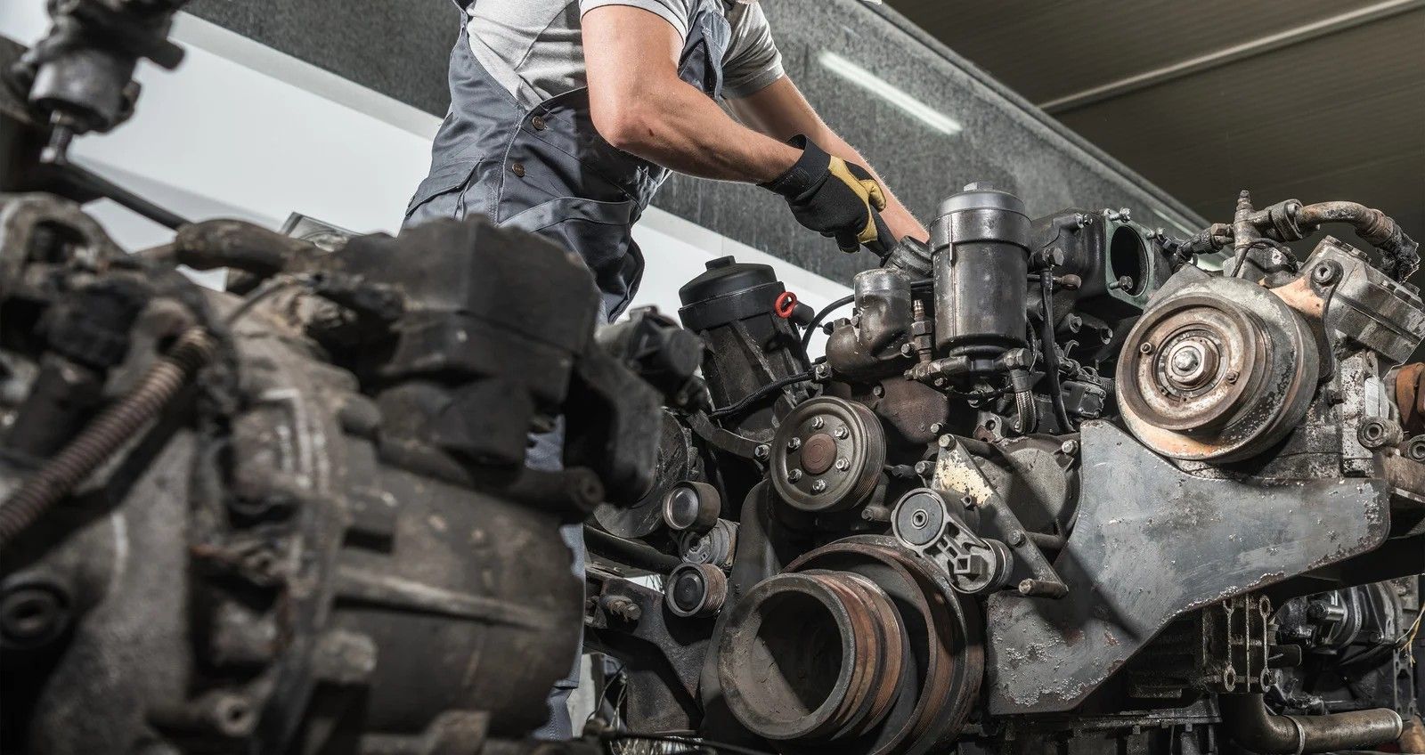 Mechanic working on a disassembled transmission. Hands are inside, holding a part. Shop environment.