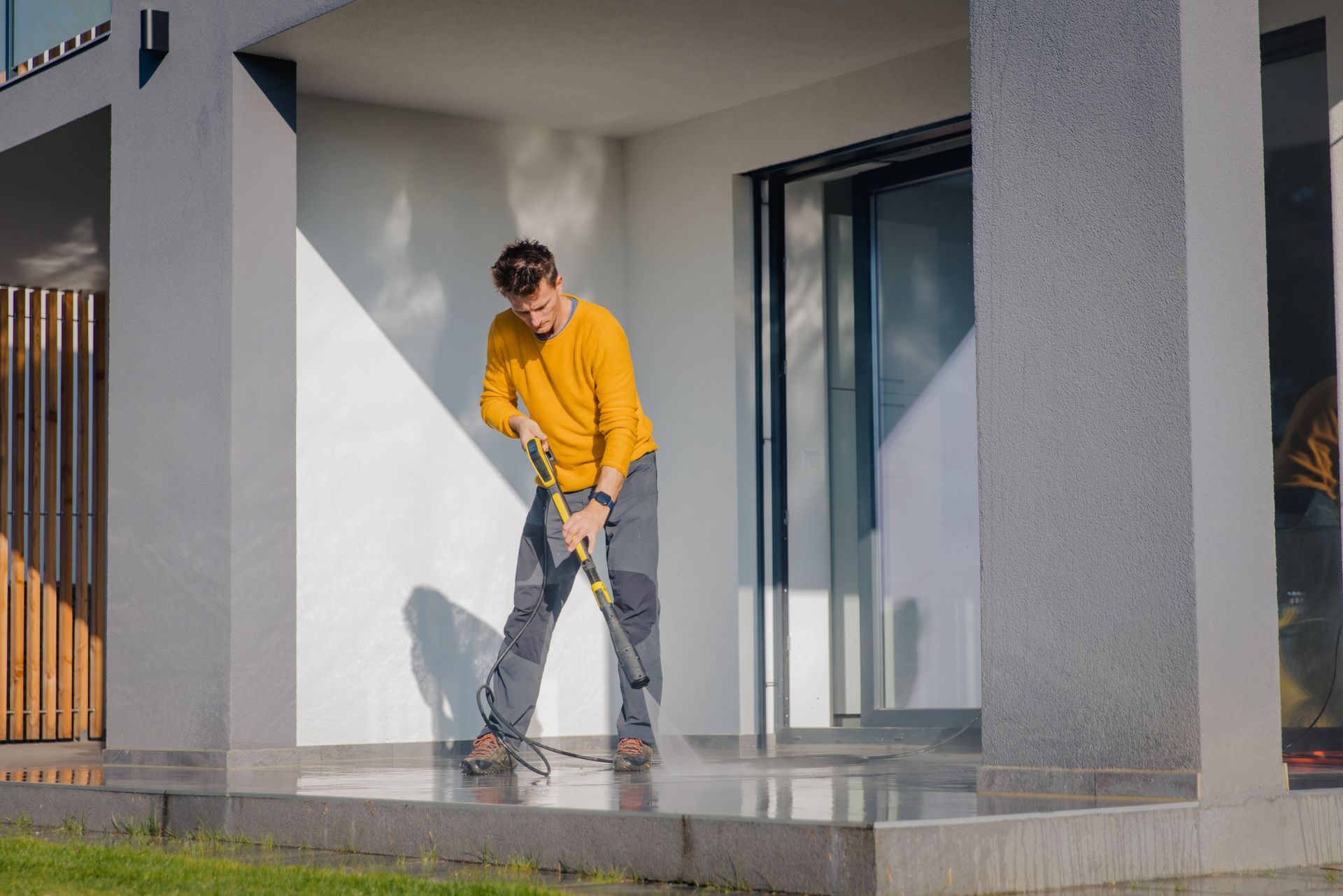 A man is cleaning a porch with a high pressure washer — North Liberty, IA — DeltaPro Painting & Remodeling