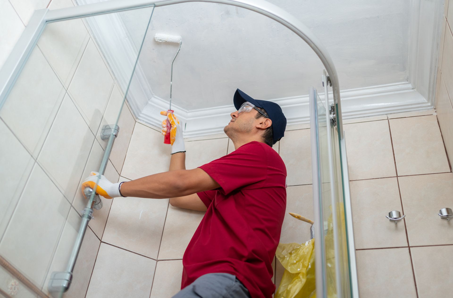 A man is painting a shower door in a bathroom — North Liberty, IA — DeltaPro Painting & Remodeling