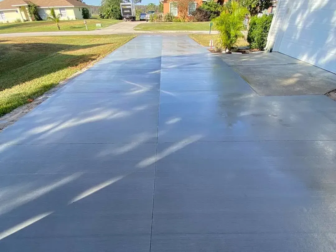A concrete driveway leading to a house in a residential area.