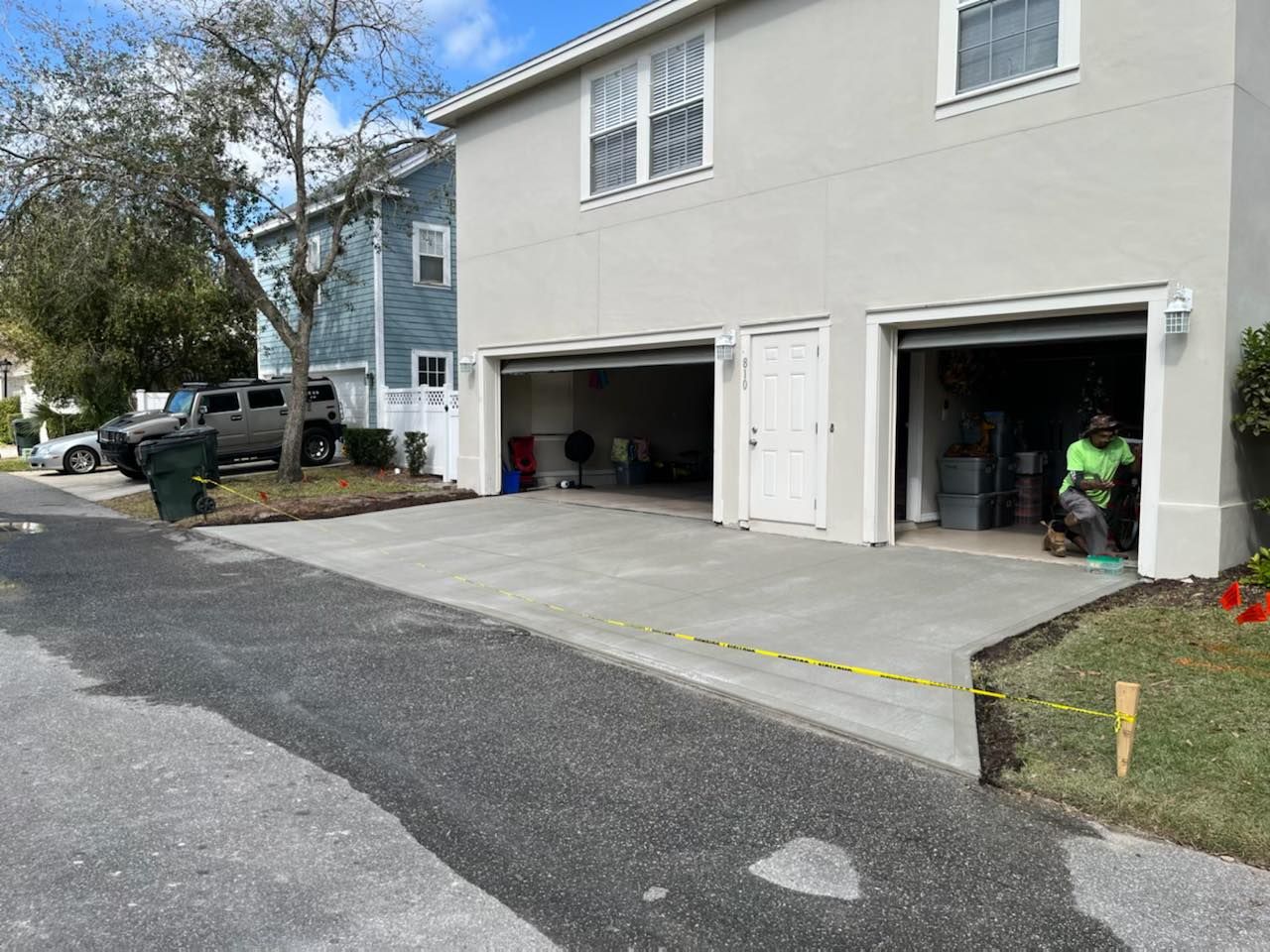 A man is standing in front of a house with two garage doors open.
