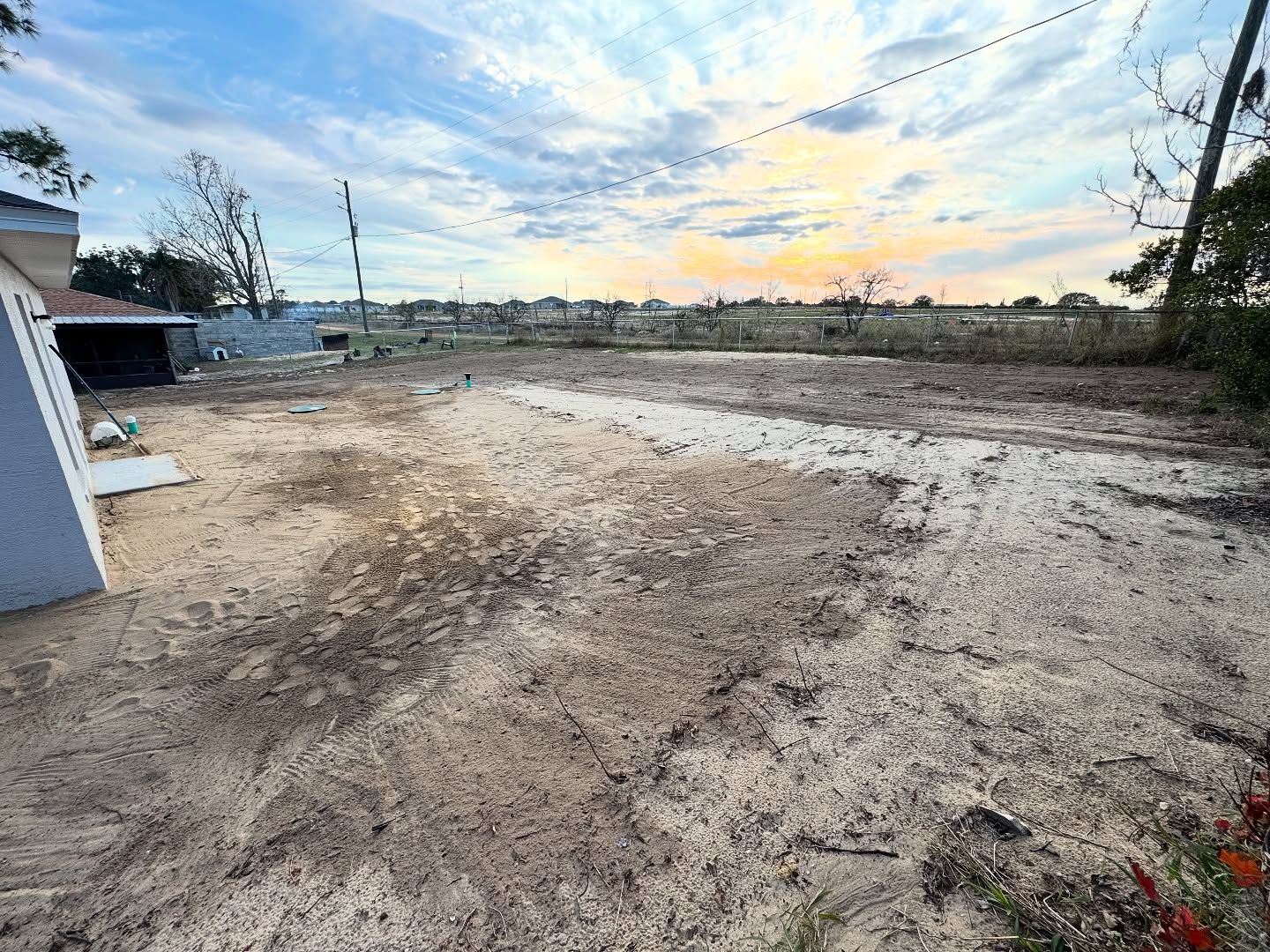 A dirt road leading to a house with a garage in the background.