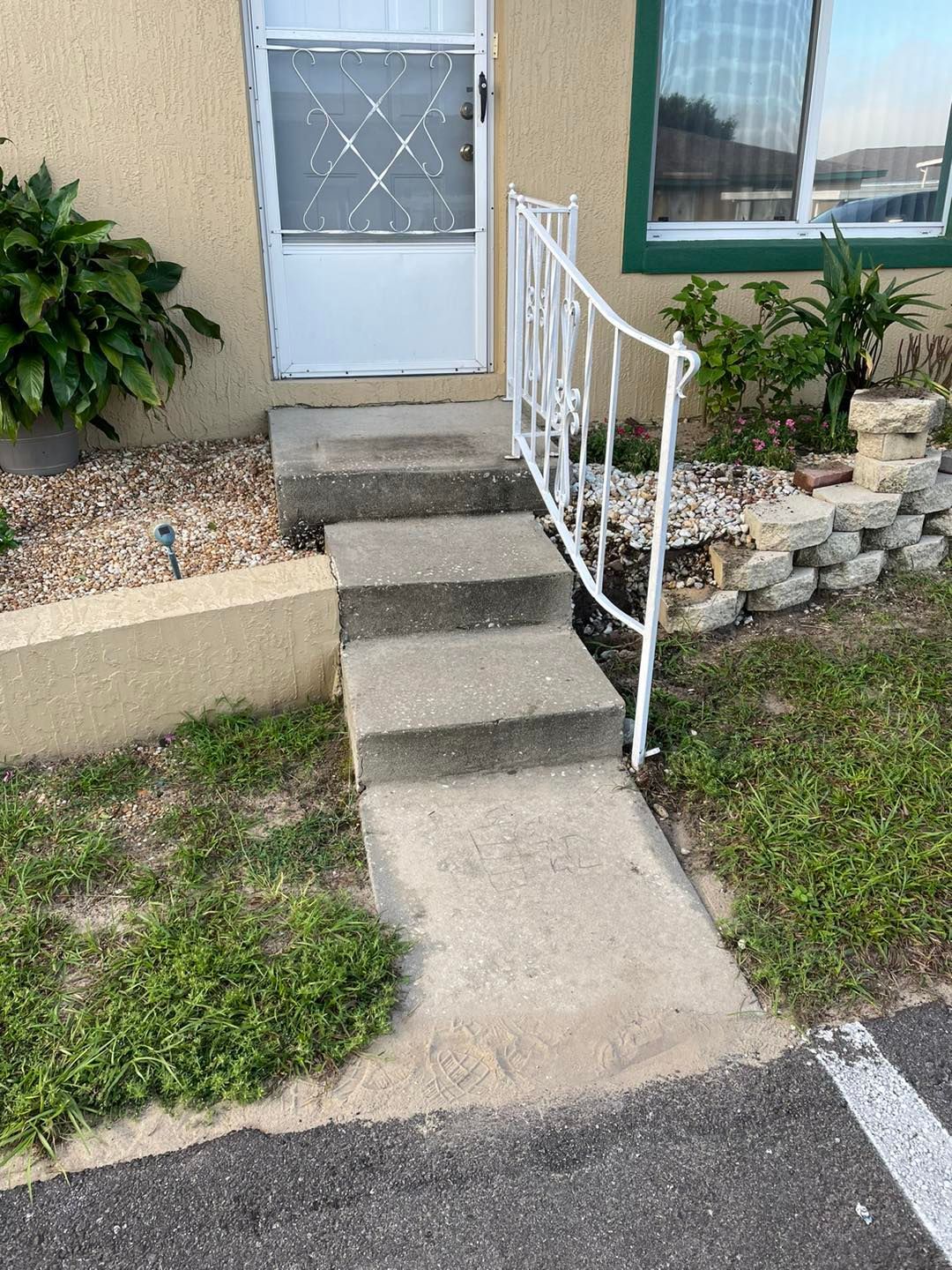 A set of stairs leading up to a house with a white railing.