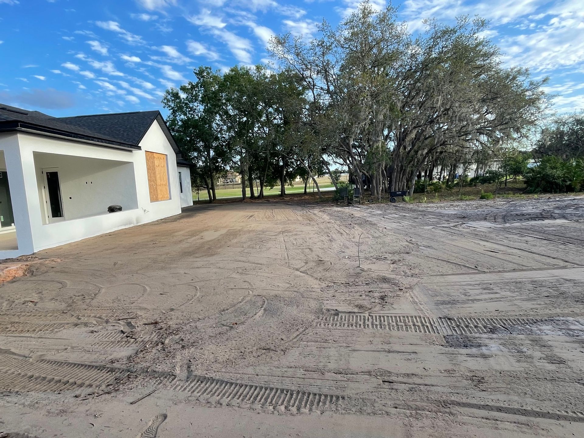 A white house is sitting in the middle of a dirt field.