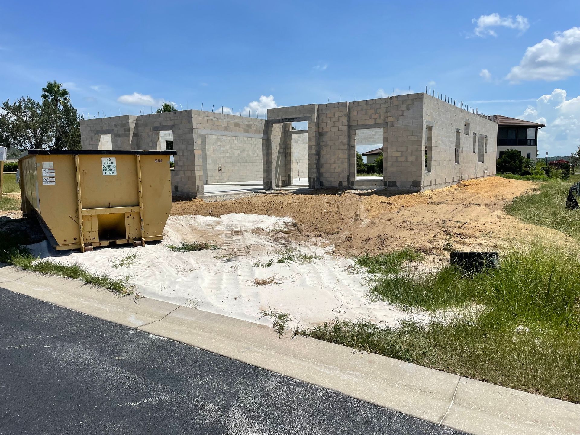A large dumpster is sitting in front of a house under construction.