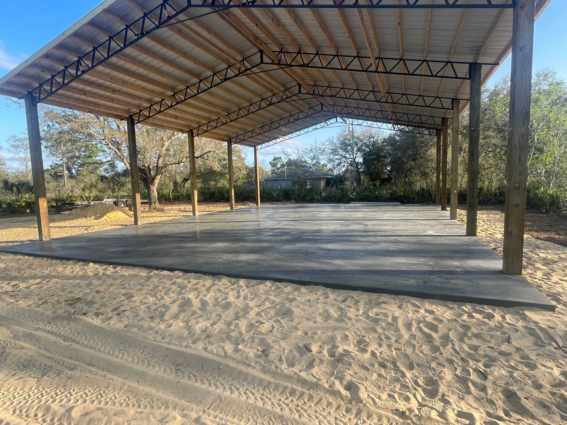 A large covered area with a wooden roof and a concrete floor.