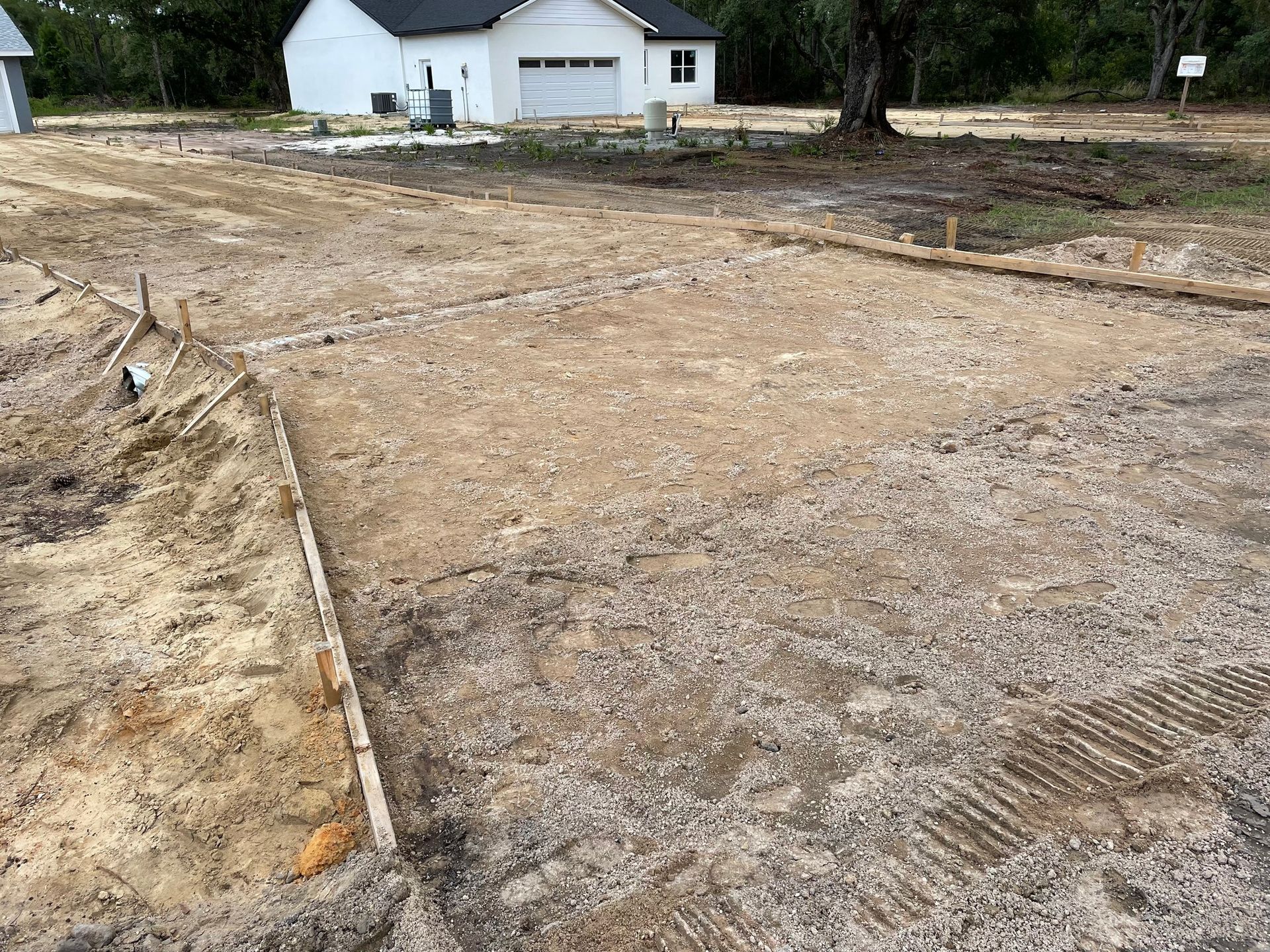 A dirt road with a white house in the background.