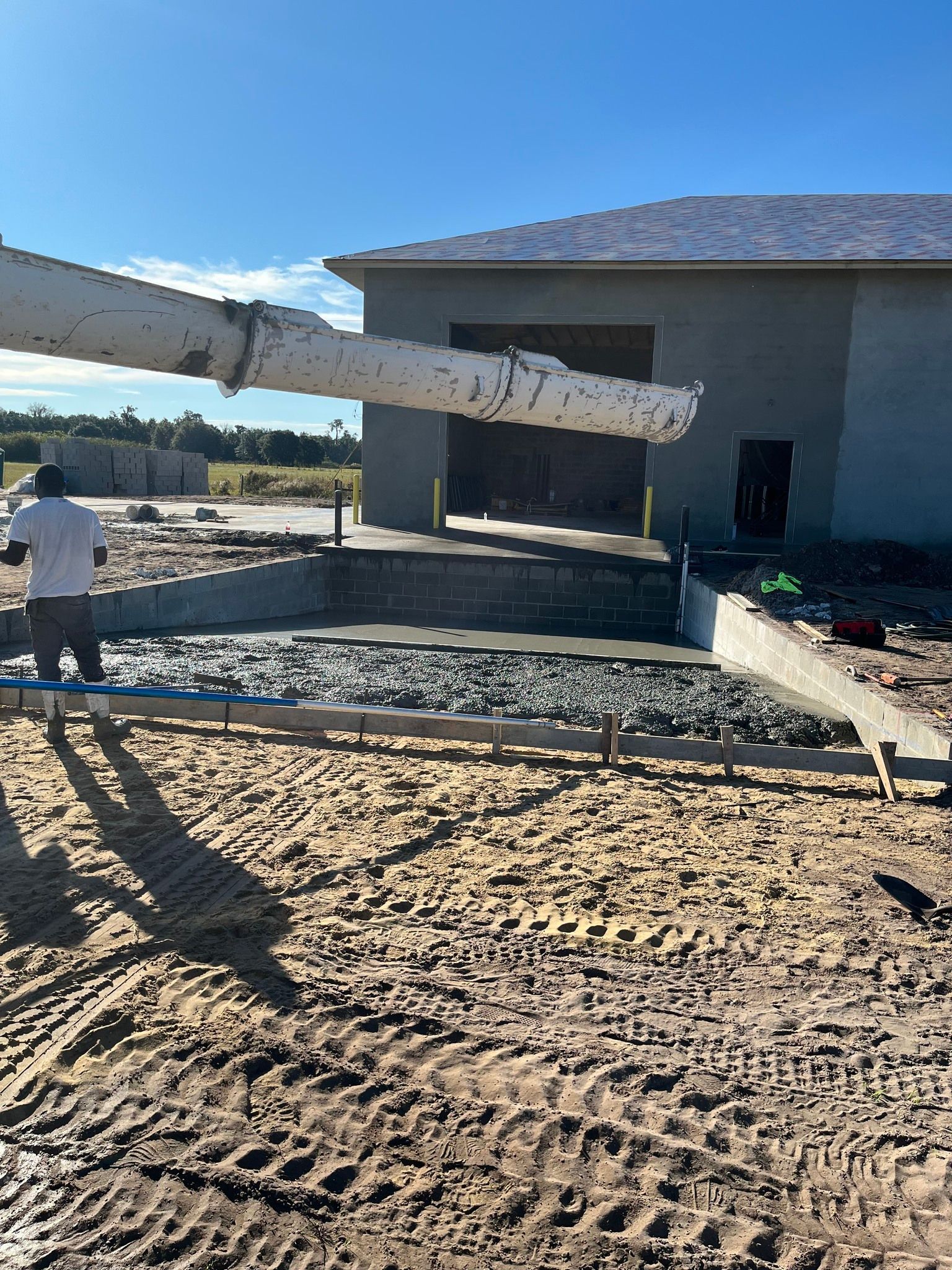 A man is standing in the dirt in front of a building under construction.