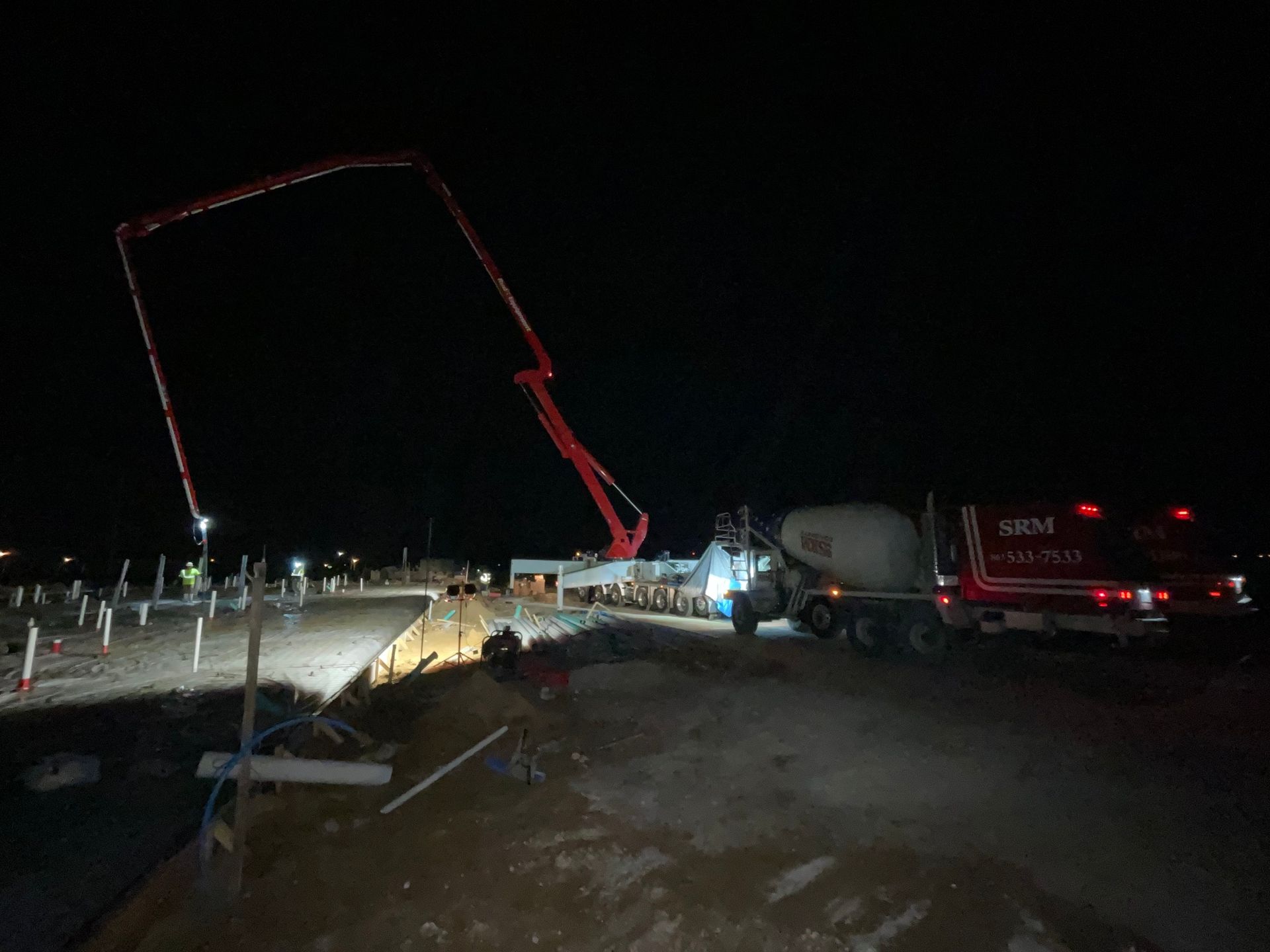 A concrete pump is pumping concrete at night on a construction site.