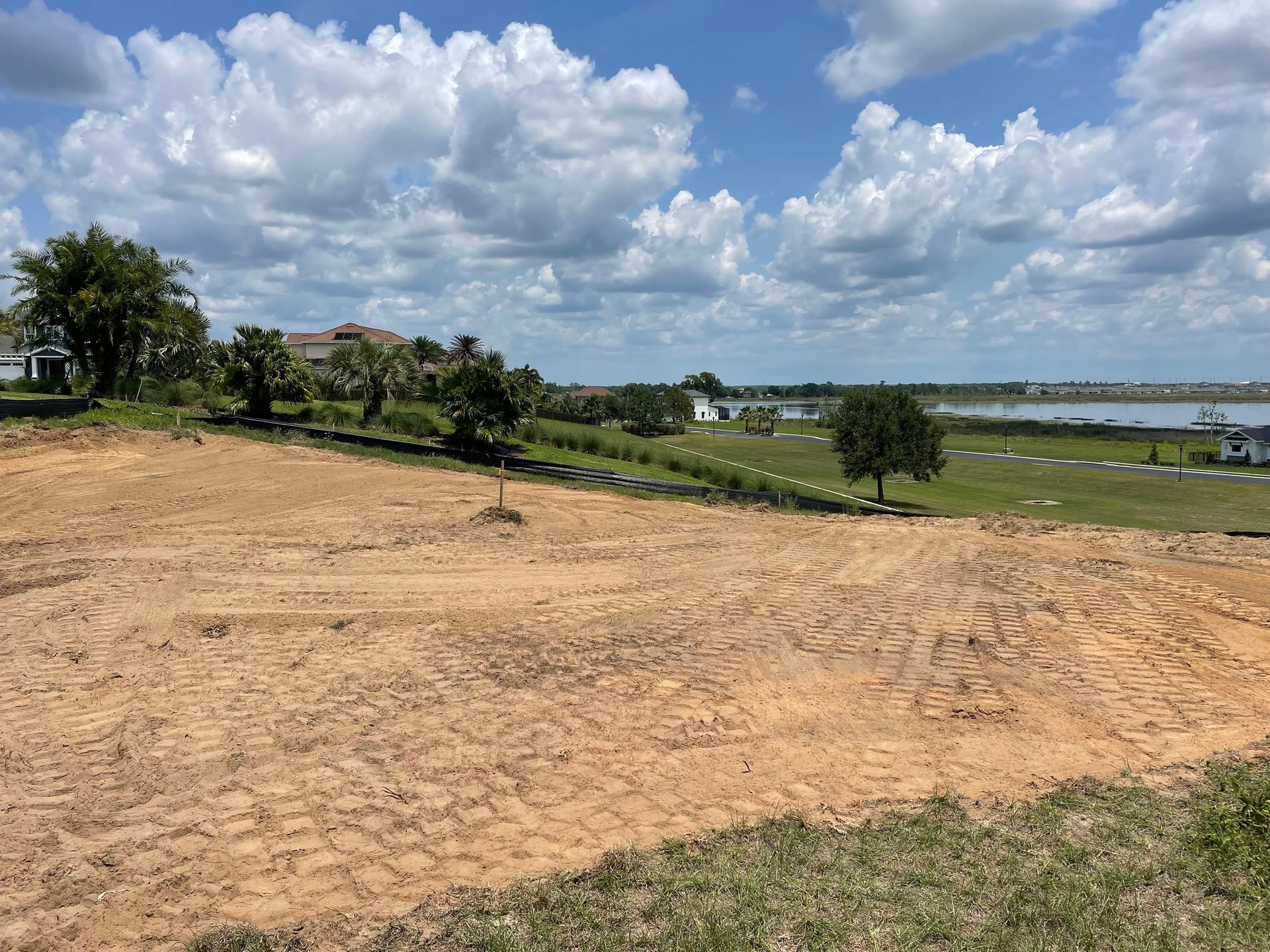 A large dirt field with a lake in the background