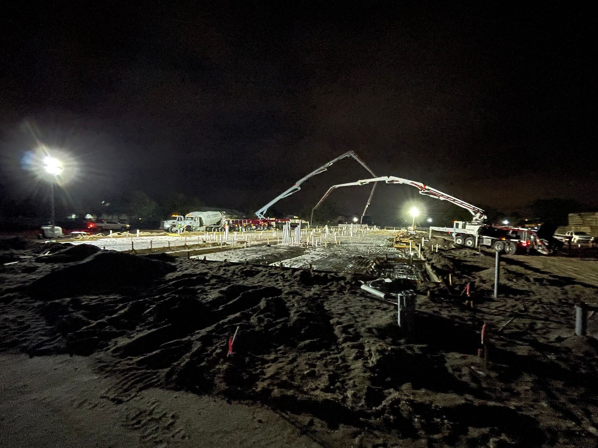 A construction site at night with a crane pumping concrete
