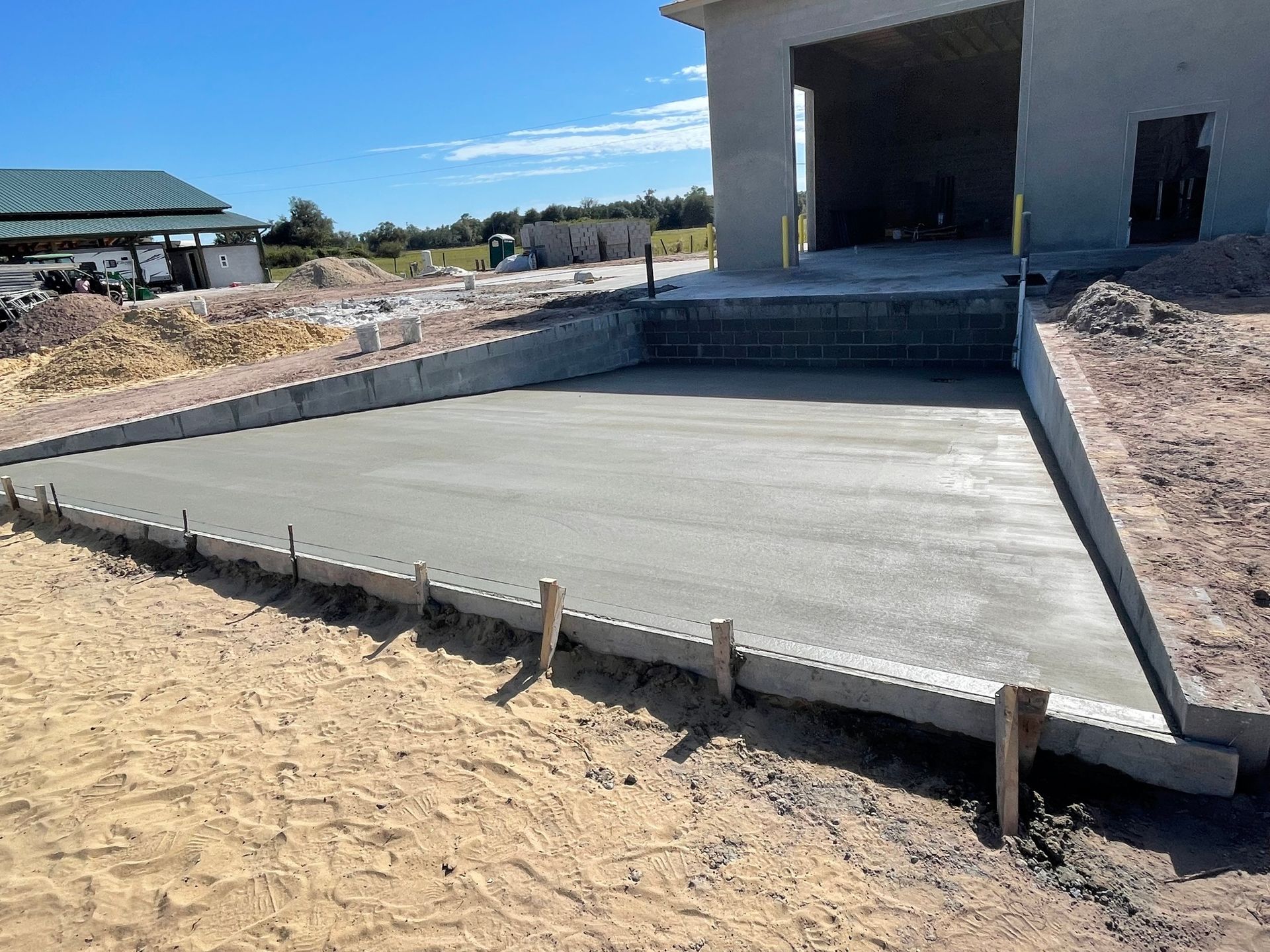 A concrete slab is being poured in front of a building under construction.