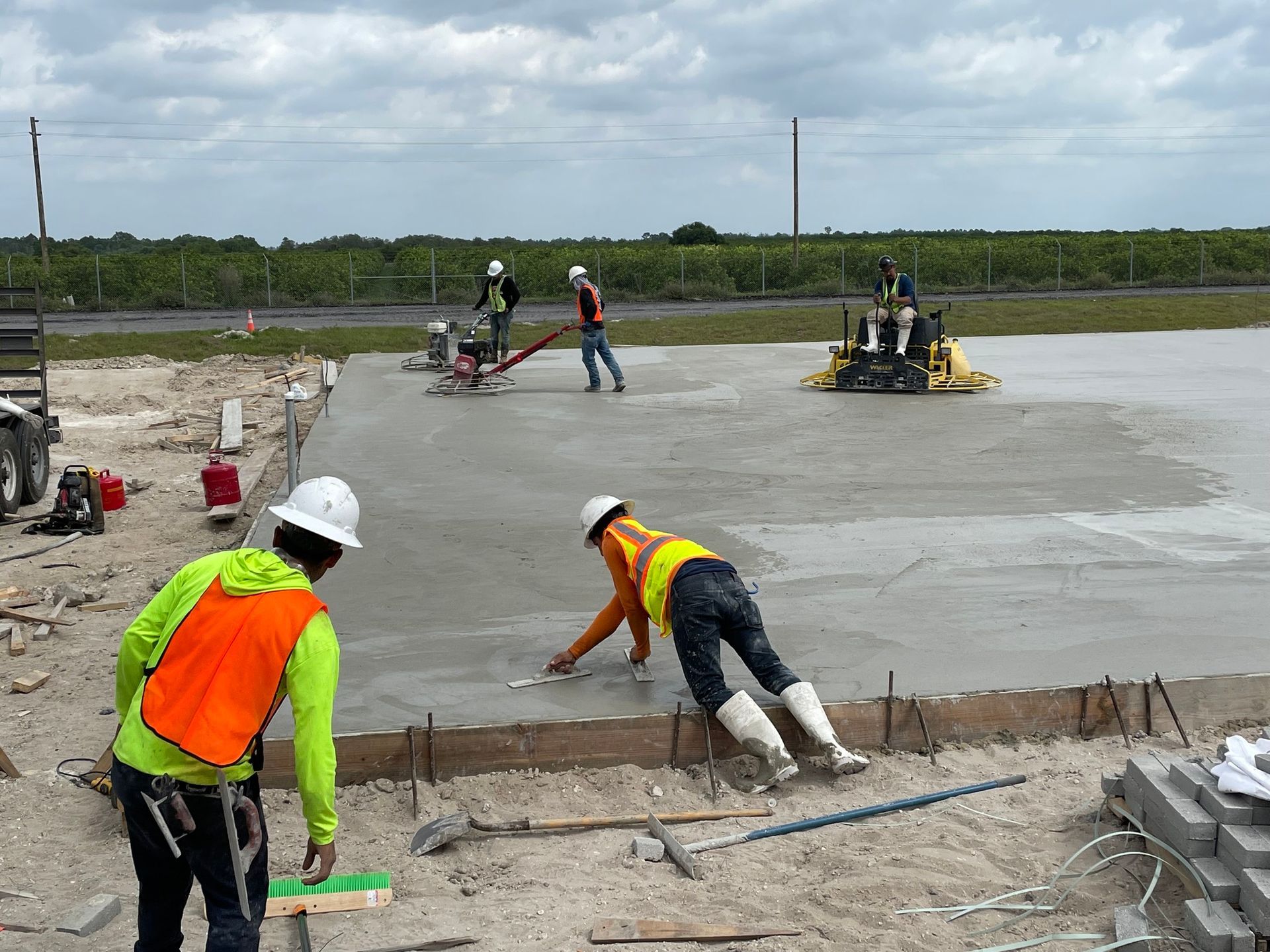 A group of construction workers are working on a concrete floor.