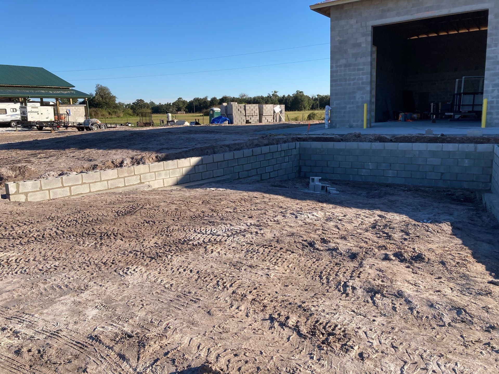 A brick building is being built in the middle of a dirt field.