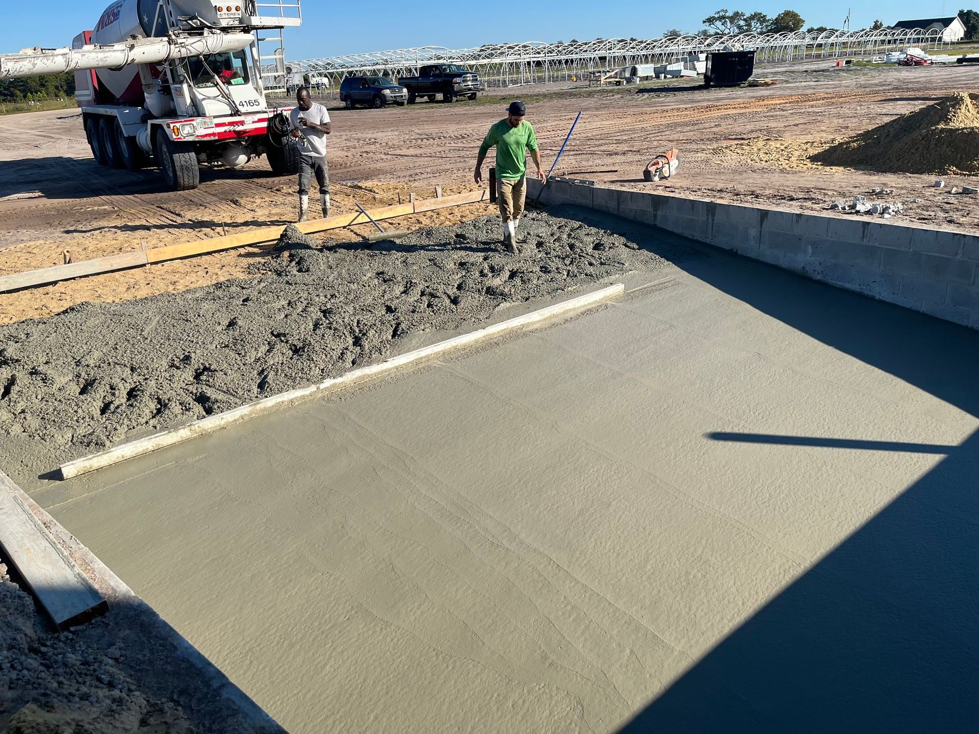 A man in a green shirt is walking on a concrete surface.